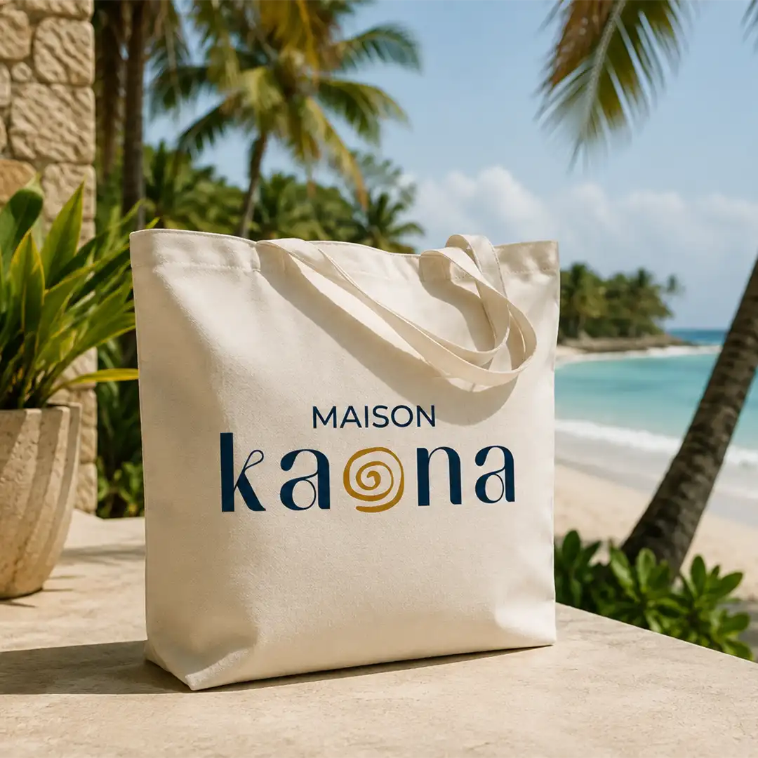 Tote bag Maison Kaona devant une plage tropicale bordée de palmiers